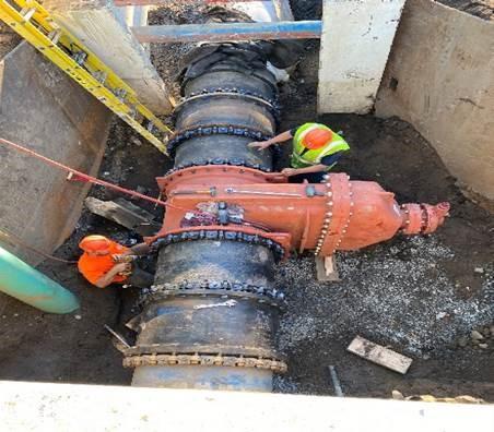 In a large pit, workers help install a new valve.