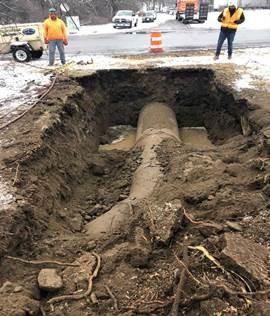 A section of curved pipe is visible in a shallow pit.