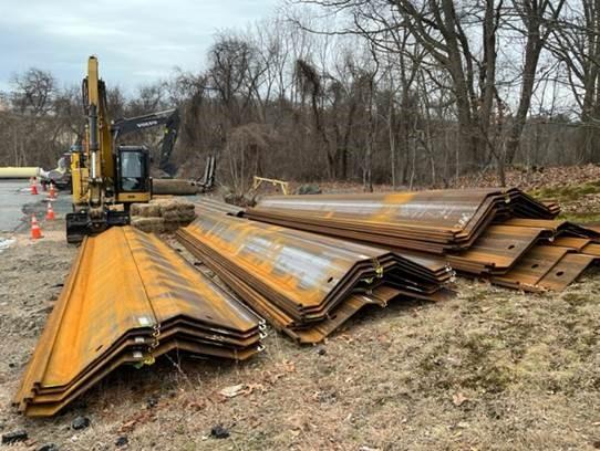 3 stacks of slightly rusty steel sheeting laying on the side of the road.