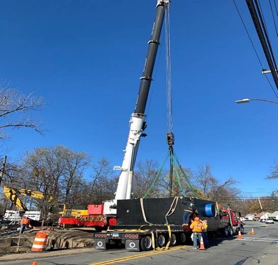 A large crane lifts something off the back of a flatbed truck.