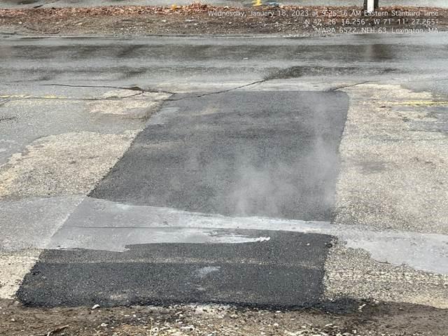 A strip of fresh asphalt over an existing road.