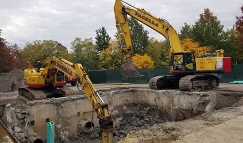 Two excavators dig out a large pit.