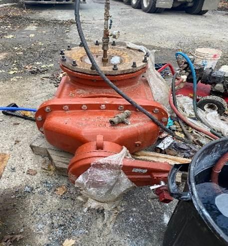A large red valve sits on a street.
