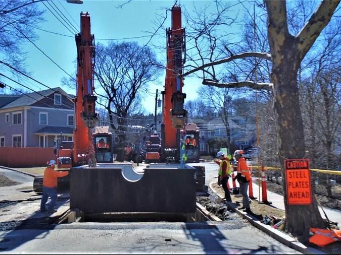 A construction crew lowers a large square into the ground.