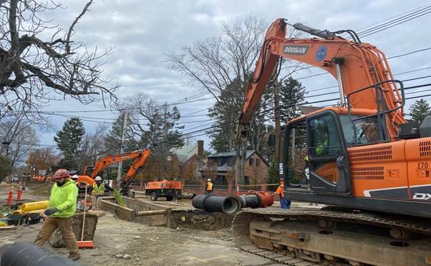 An excavator works on digging out a hole on a residential street.