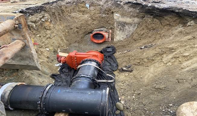 A watermain with a gap in it in a dug out whole.