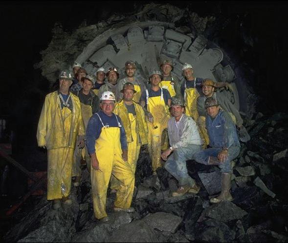 Construction workers posing in front of tunnel boring machine.