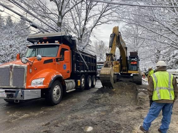 An excavator digs dirt into a dump truck. 